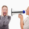 Young manager yelling at her employee through a megaphone against a white background